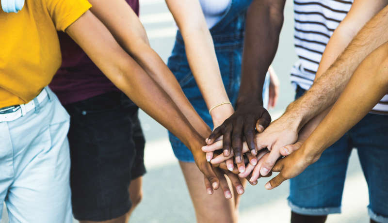 Close up multi ethnic group of young students stacking hands together - Millennial people celebrating together outdoor - College students teamwork stacking hand Concept